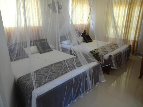 a bedroom with two beds and a table and curtains at Abha Villa in Galle