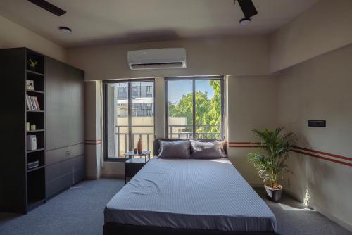 a bedroom with a bed and a large window at FLH Residences, Ambawadi in Ahmedabad