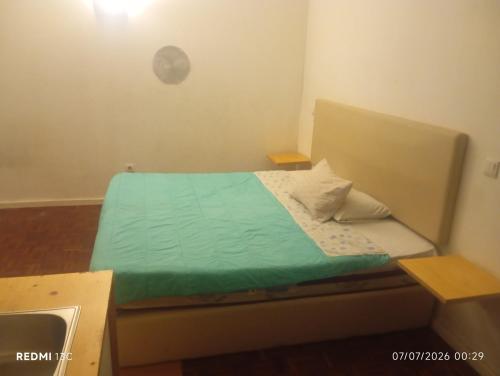 a small bedroom with a bed with a green comforter at Telhado solitario in Porto