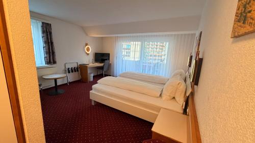 a room with two beds and a desk in it at Hotel Heilquelle-Leukerbad-Therme in Leukerbad