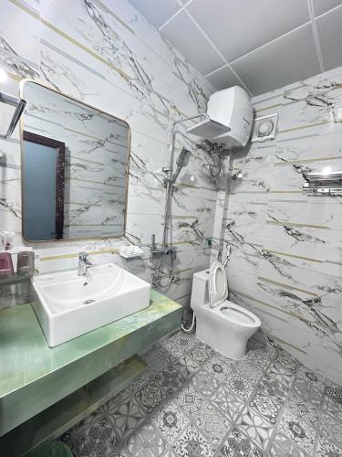 a bathroom with a sink and a toilet and a mirror at Cloudy Hotel in Ha Giang