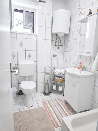a white bathroom with a toilet and a sink at Abrazo in Orašje