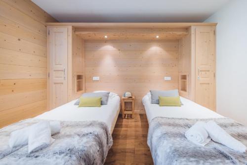 two beds in a room with wooden walls at L'Auberge Nordique in Le Grand-Bornand