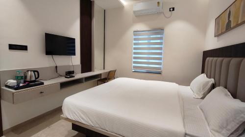 a bedroom with a white bed and a television at 7 Pearls in Gajendragarh