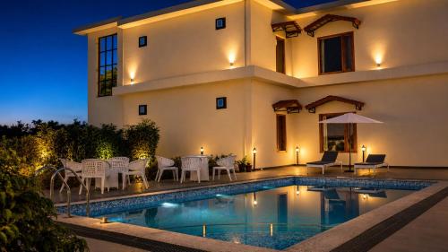 a villa with a swimming pool at night at Gauri Hayat Corbett Retreat in Rāmnagar