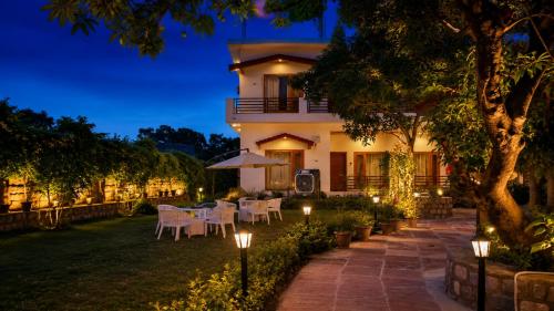 a building with a table and chairs and lights at Gauri Hayat Corbett Retreat in Rāmnagar