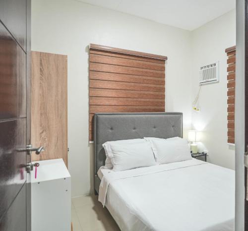 a bedroom with a white bed and a wooden headboard at Manzil Anilao B&B in Mabini