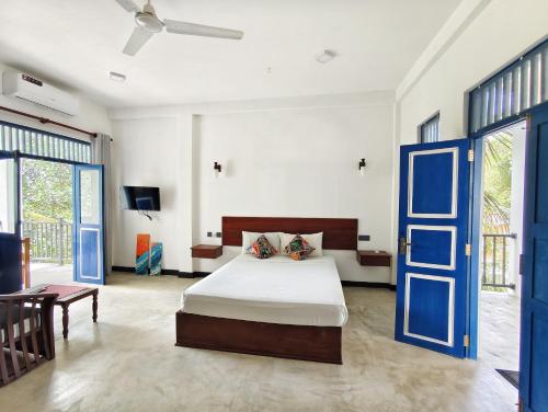a bedroom with a bed and a blue door at Sundaze Villa in Goyambokka