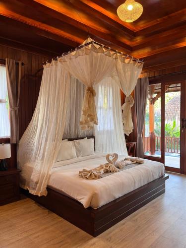 a bedroom with a canopy bed with white drapes at Villa Lumbung Sidemen in Sidemen