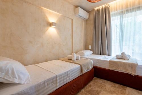 two beds in a room with a window at Terra Elea Luxury Pool Suite Aura in Nikiti