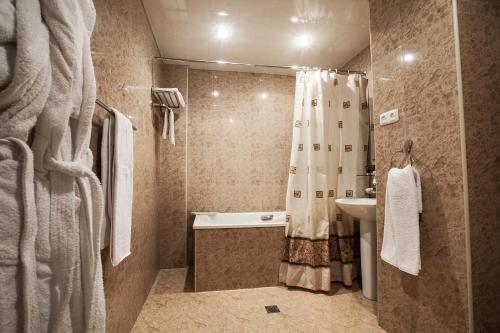 a bathroom with a shower and a tub and a sink at Aviatrans Hotel in Yerevan