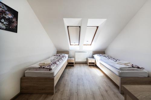 two beds in a room with two windows at Penzión Bergmannhof in Ladomer