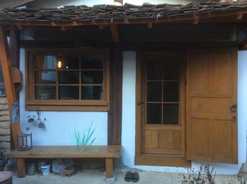 una casa con dos puertas y un banco delante en Yangsajae en Jeonju