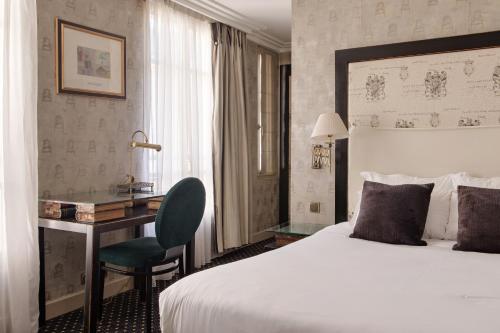 a hotel room with a large bed and a desk at Villa Lutèce Port Royal in Paris