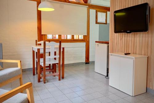 a room with a table and a tv and a table and chairs at Los Techos Apart in Esquel