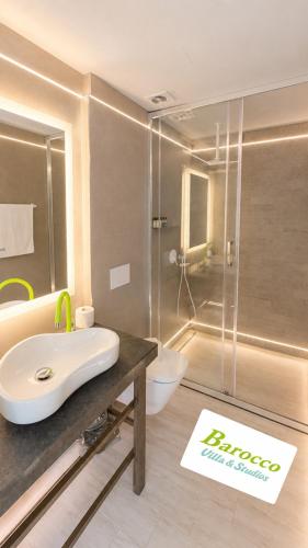a bathroom with a sink and a glass shower at Barocco Villa & Studios in Potamiá