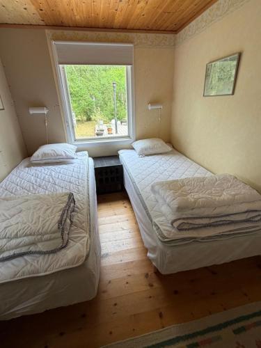 two beds in a room with a window at Havsnära fritidshus in Åhus