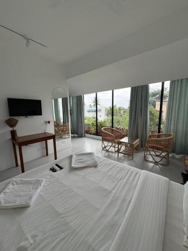 a white bedroom with a large white bed and windows at The Balified Villa in Pondicherry