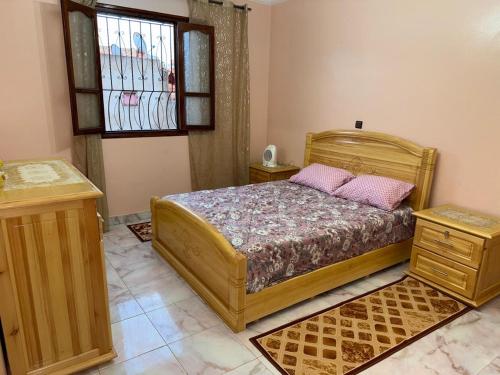 a bedroom with a wooden bed and a window at Samadis Home 3 in Larache