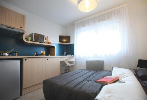 a bedroom with a bed with a red book on it at Résidence Les Portes d'Espagne in Perpignan