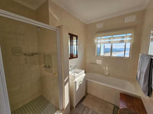 a bathroom with a tub and a sink and a shower at On The Beach Scottburgh in Scottburgh