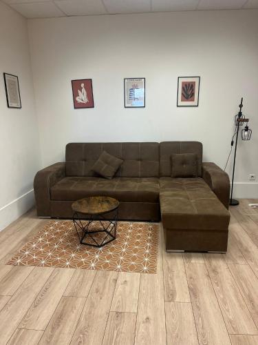a living room with a brown couch and a table at Gentilly - Studio spacieux in Gentilly