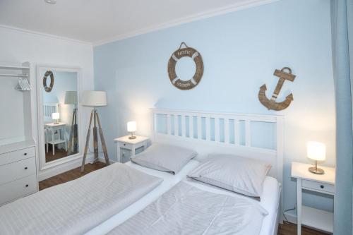 a white bedroom with two beds and a mirror at Düne, App 7 in Duhnen