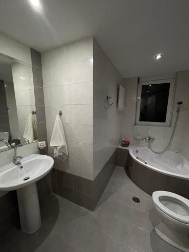 a bathroom with a sink and a tub and a toilet at Cozy beach apartment in Saronida in Saronida