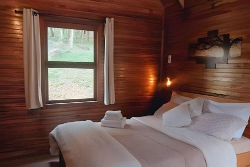 a bedroom with a white bed with a window at Cabana surucuã in Três Coroas