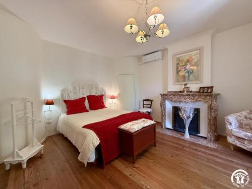 a bedroom with a bed with red pillows and a fireplace at La calade in Douzens
