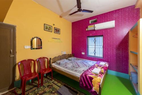 a bedroom with a bed and two red chairs at Mangrove Pitta - Bhitarkanika in Kendrāparha