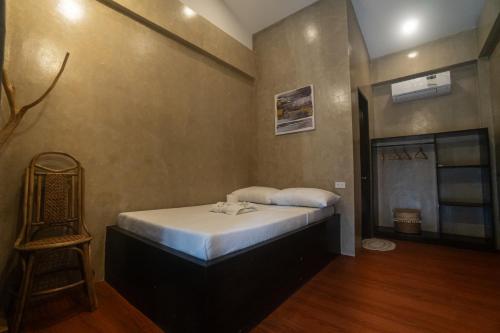 a bedroom with a bed and a chair in it at Azarria Siargao Villas in General Luna