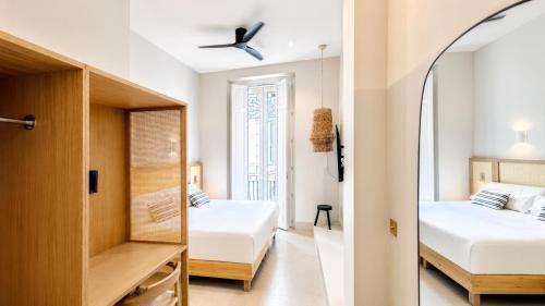 a bedroom with two beds and a mirror at Cosy Rooms Tapinería in Valencia