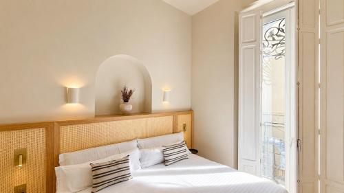 a bedroom with a bed with white sheets and a window at Cosy Rooms Tapinería in Valencia