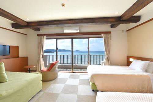 a bedroom with two beds and a view of the ocean at Ishigaki Seaside Hotel in Ishigaki Island