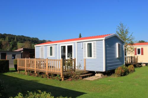 une petite maison bleue avec une terrasse en bois dans l'établissement Camping Le Marqueval, à Pourville-sur-Mer