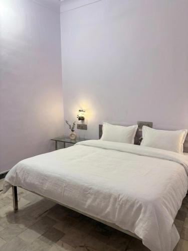 a large white bed with white sheets and pillows at Vyom Hostel in Pushkar