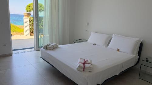 a bedroom with a white bed with a view of the ocean at Sunset Bay in Torre Suda