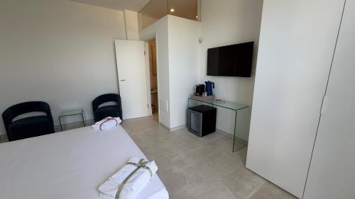 a hotel room with a white bed and a television at Sunset Bay in Torre Suda