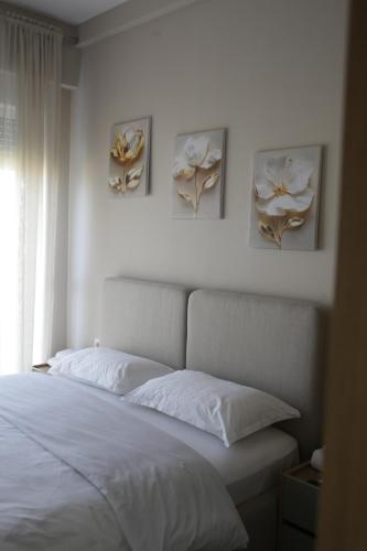 a bedroom with a bed with three paintings on the wall at Boulevard View in Tirana