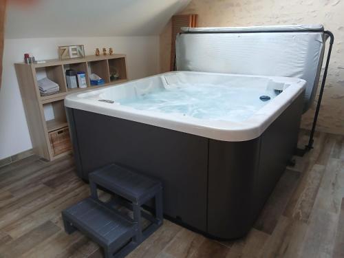 a large bath tub with a stool in a bathroom at Mise au Verre in Prémeaux