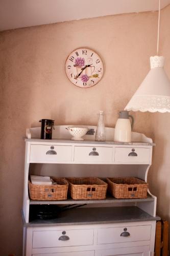 a clock on the wall above a shelf with baskets at Casa de la Panadería in Los Navalucillos
