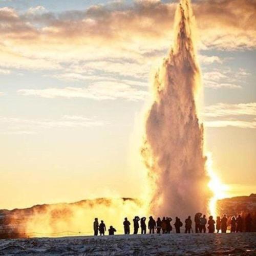 a group of people standing around a bonfire at Hotel Geysir in Geysir