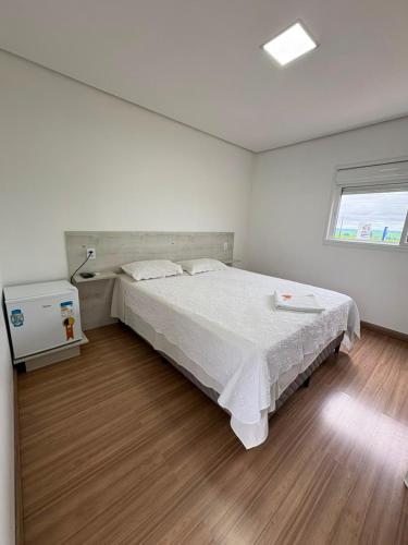 a bedroom with a large white bed and a window at Hotel Vanguarda Tapera in Tapera