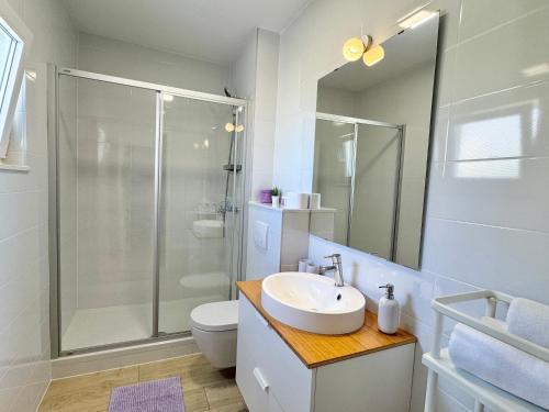 a white bathroom with a shower and a sink at Ksenija Apartments in Tučepi