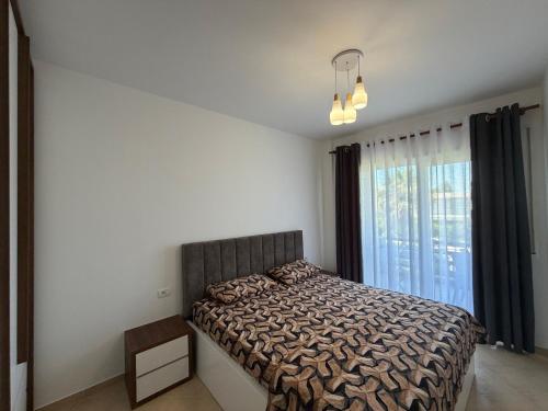 a bedroom with a bed and a large window at Near movenpic apartament in Draç