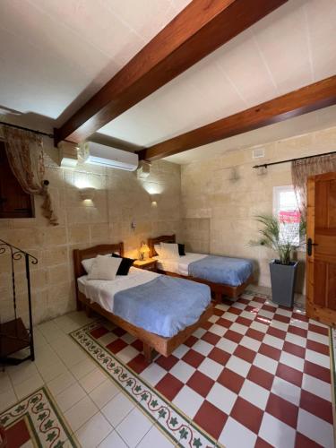 a bedroom with two beds and a checkered floor at Kercem Boutique Farmhouse in Kerċem