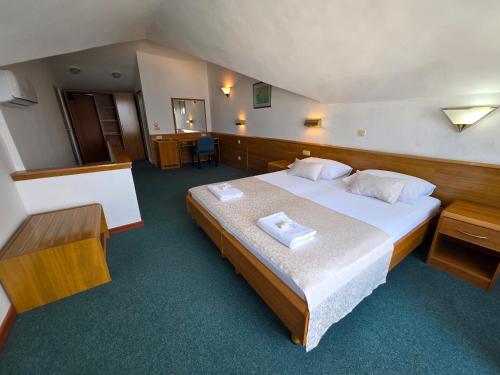 a bedroom with a large bed with two towels on it at Hotel Stella in Neum