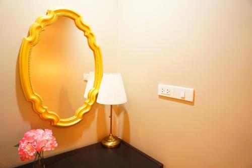a mirror on a wall with a lamp on a table at Taris Art Hotel Phrae in Phrae