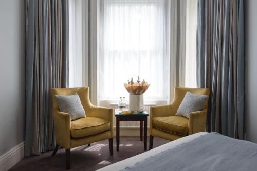 a bedroom with two chairs and a table and a window at Connaught Lodge in Bournemouth
